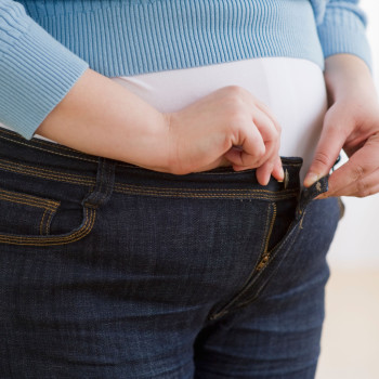 Overweight woman buttoning up her jeans. Image shot 2010. Exact date unknown.