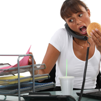 Busy woman eating at her desk